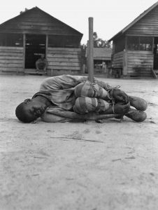 A prisoner tied around a pickaxe for punishment, Georgia, 1932.