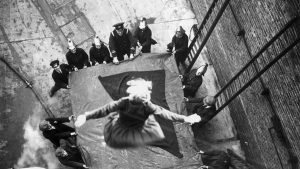 A daring female firefighter leap from a second-floor window, 1928.